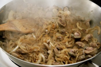 Adding kidneys to browned onions and giving them a quick stir