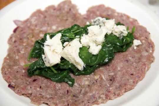 Minced meat spread on a plate with spinach stuffing