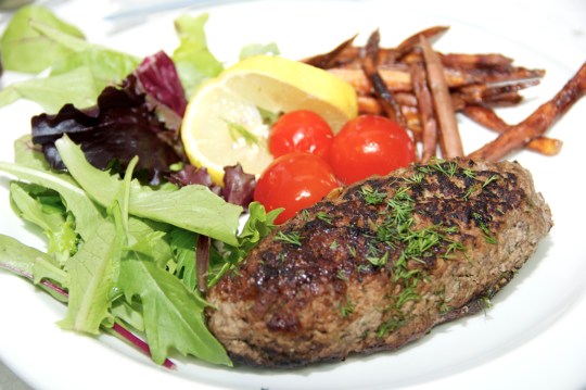 Spinach Stuffed Lamb Cutlets served with field greens, pickled tomatoes, sweet potato fries and a slice of lemon