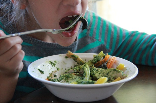 Kid enjoying Spinach & Pumpkin Seed Pesto Pasta with Chicken